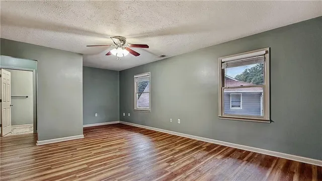 a view of an empty room with window and wooden floor