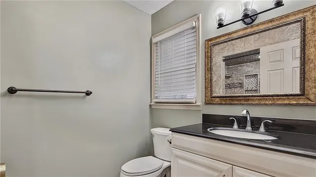 a bathroom with a granite countertop toilet sink and mirror