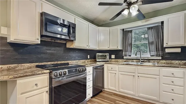 a kitchen with stainless steel appliances granite countertop a sink a stove and cabinets