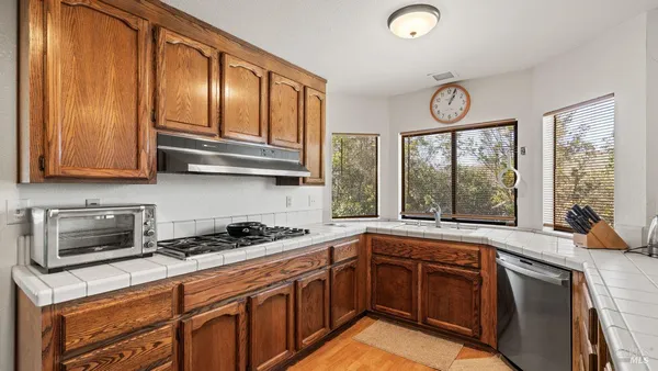 a kitchen with stainless steel appliances granite countertop wooden cabinets a stove a sink and dishwasher next to a window