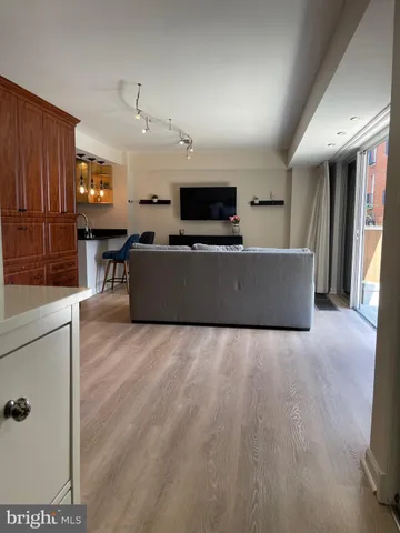 a living room with stainless steel appliances furniture a flat screen tv and a refrigerator