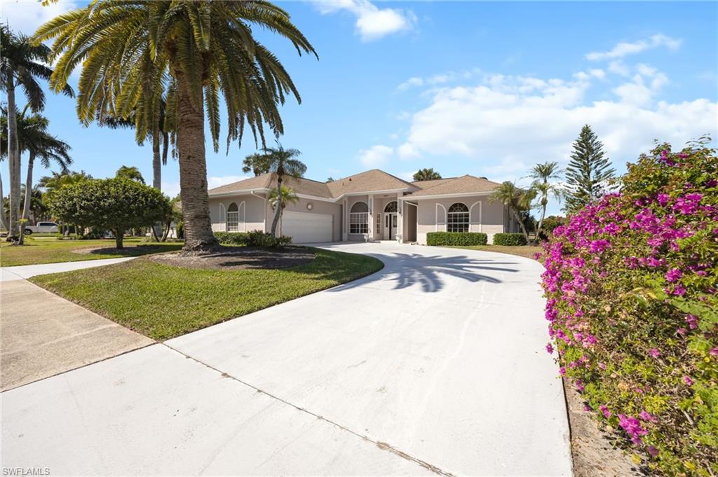 867 St Andrews Boulevard Naples, FL 34113 - Photo 3 of 28 a front view of a house with a yard and palm trees
