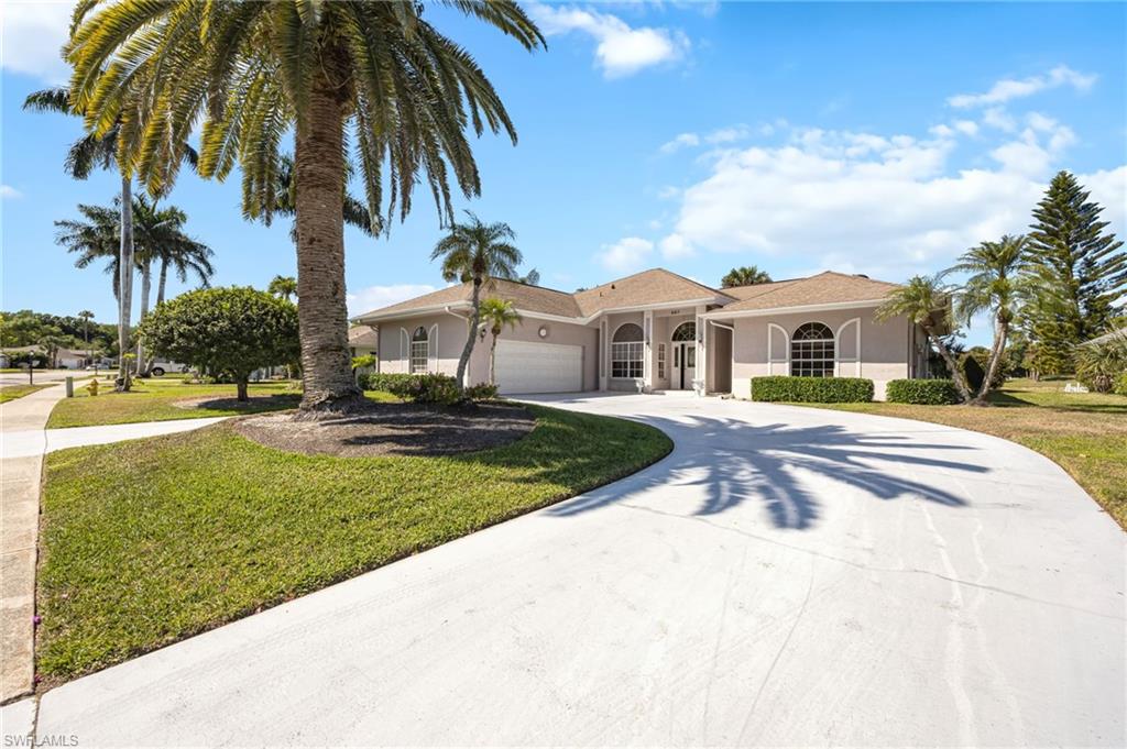 867 St Andrews Boulevard Naples, FL 34113 - Photo 5 of 28 a view of a white house with a small yard plants and palm trees