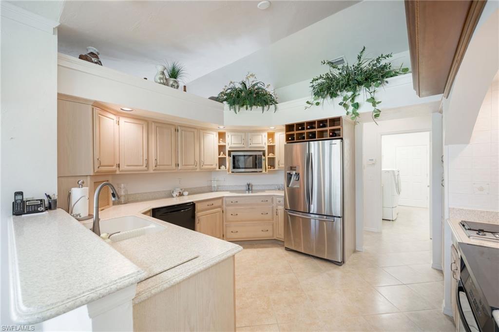 867 St Andrews Boulevard Naples, FL 34113 - Photo 10 of 28 a kitchen with a refrigerator and a sink