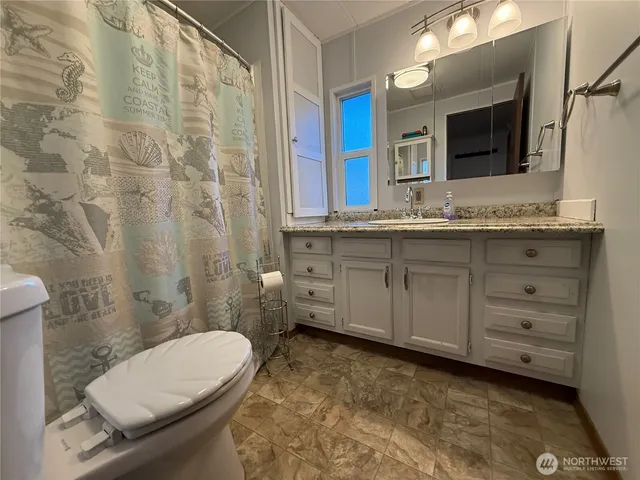 a bathroom with a granite countertop toilet sink and mirror