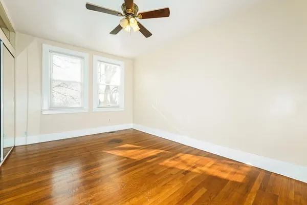 a view of empty room with wooden floor and fan