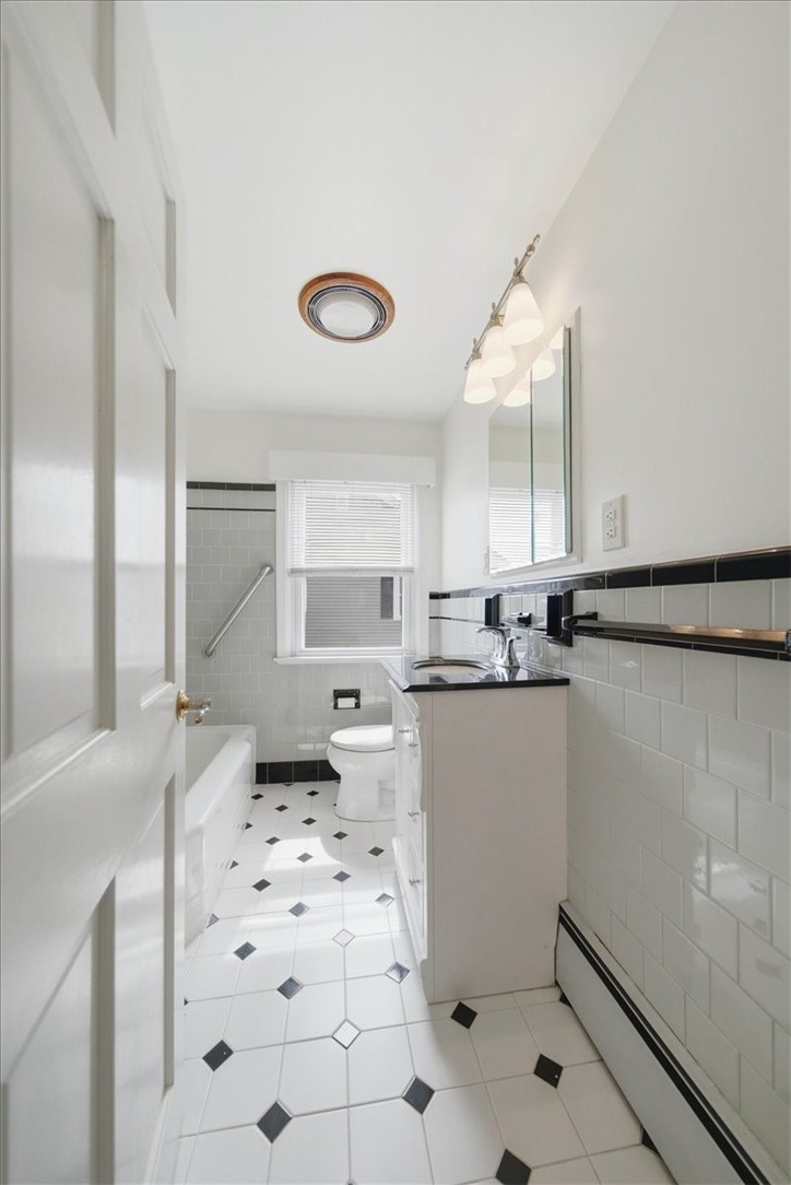 80 Maplecrest Drive Pawtucket, RI 02861 - Photo 22 of 44 Beautifully preserved vintage bathroom featuring classic black-and-white tilework, including a full tiled tub surround with contrasting accent trim and a timeless hex tile floor.