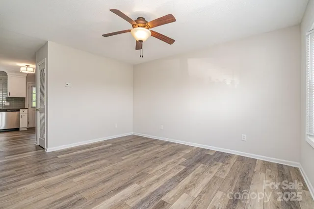 an empty room with wooden floor and a ceiling fan