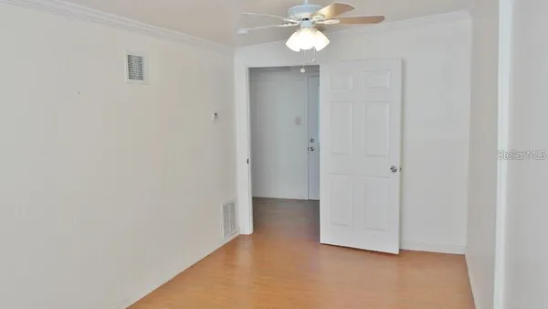 an empty room with a fan & a window