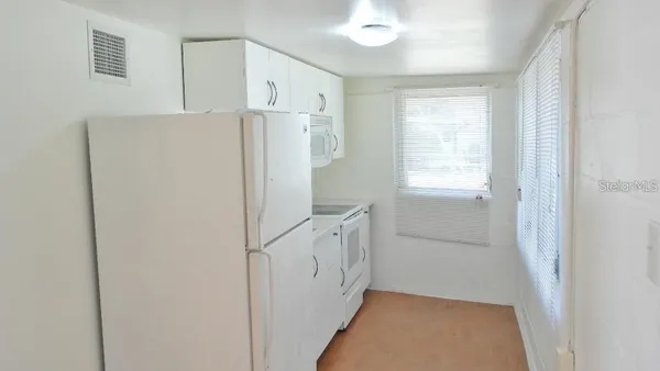 a view of a kitchen with white cabinets and refrigerator