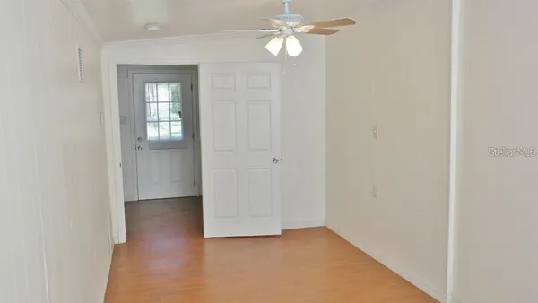an empty room with windows and fan