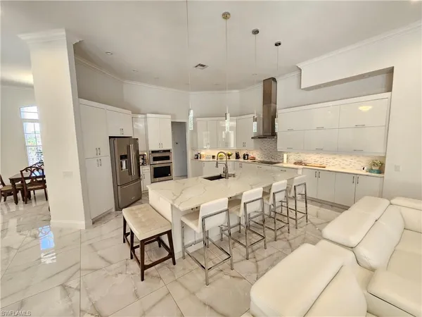 a kitchen with stainless steel appliances kitchen island granite countertop a table chairs sink and cabinets