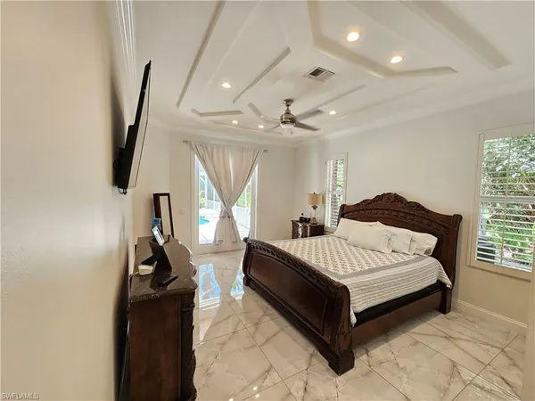 a spacious bedroom with a bed and a flat tv screen on the dresser