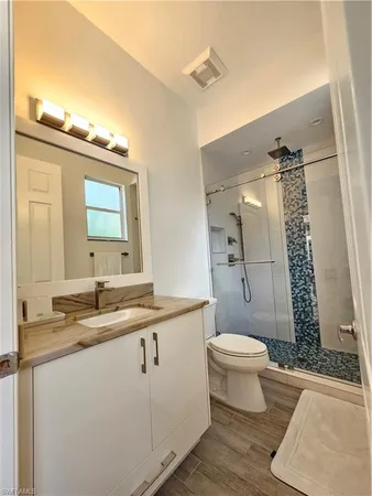 a bathroom with a granite countertop sink toilet a mirror and shower