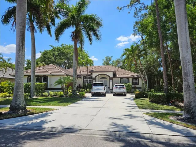 a view of a house with a yard and palm trees