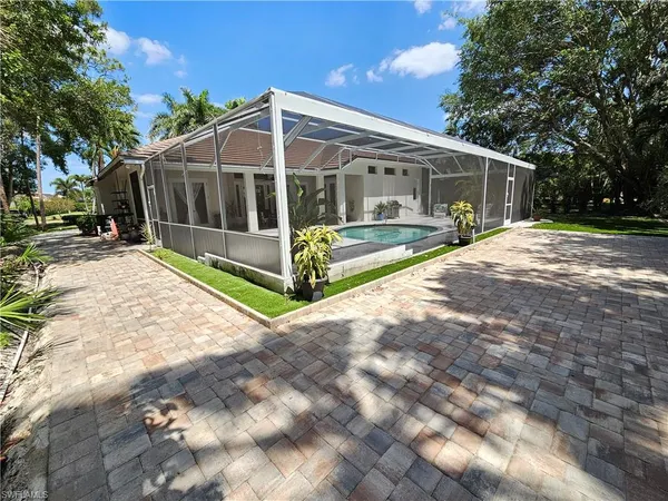 a view of a house with backyard and trees in the background