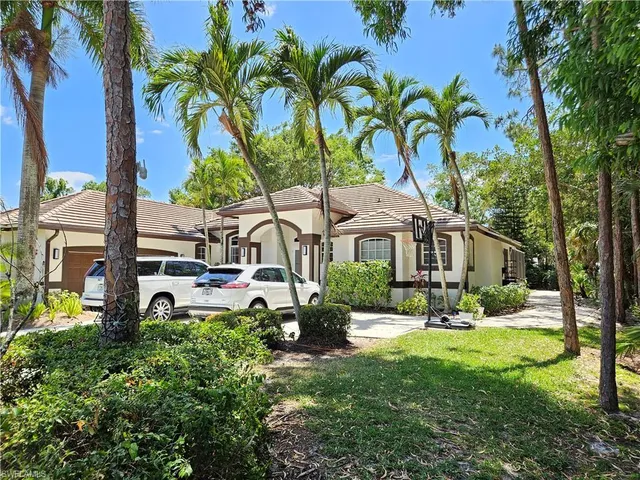 a front view of a house with garden and trees