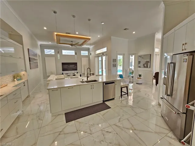 a large white kitchen with lots of counter space a refrigerator and a fireplace
