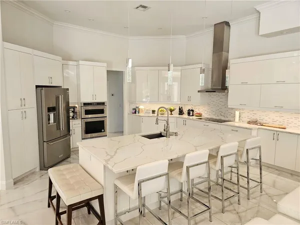 a kitchen with stainless steel appliances kitchen island granite countertop a table chairs and a refrigerator