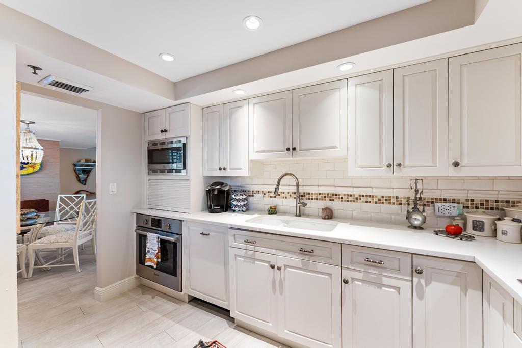 200 Ocean Trail Way, Unit T7 Jupiter, FL 33477 - Photo 15 of 46 a kitchen with stainless steel appliances granite countertop white cabinets sink and stove
