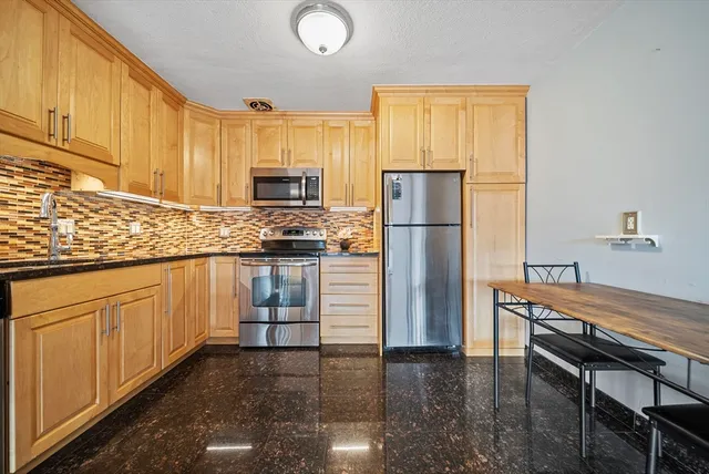 a kitchen with granite countertop a refrigerator stove top oven and sink