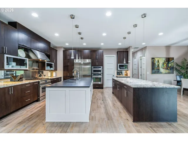 a kitchen with stainless steel appliances kitchen island granite countertop a stove top oven a sink a counter top space and cabinets