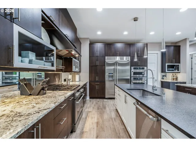 a kitchen with stainless steel appliances granite countertop a sink a stove and a wooden floors