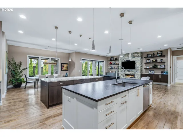 a kitchen with stainless steel appliances granite countertop a sink a stove and a wooden floors