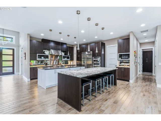 a kitchen with stainless steel appliances kitchen island granite countertop a stove top oven a sink and a refrigerator