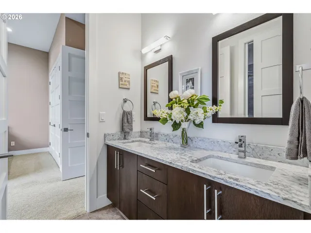 a bathroom with a granite countertop double vanity sink and mirror