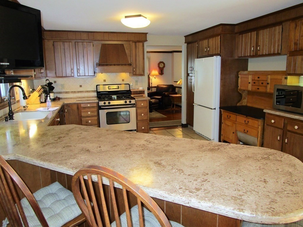1209 Amostown Road West Springfield, MA 01089 - Photo 4 of 29 a kitchen with a refrigerator a stove a sink a counter space and cabinets