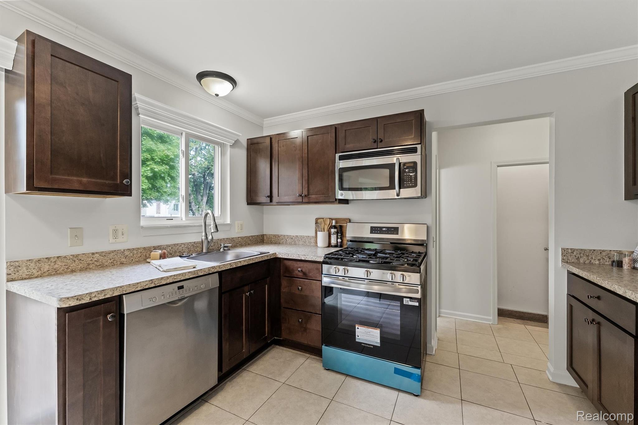 39861 Rager Court Clinton Township, MI 48038 - Photo 9 of 26 Kitchen featuring dark wood cabinetry, light-toned countertops, stainless steel appliances, and tiled flooring