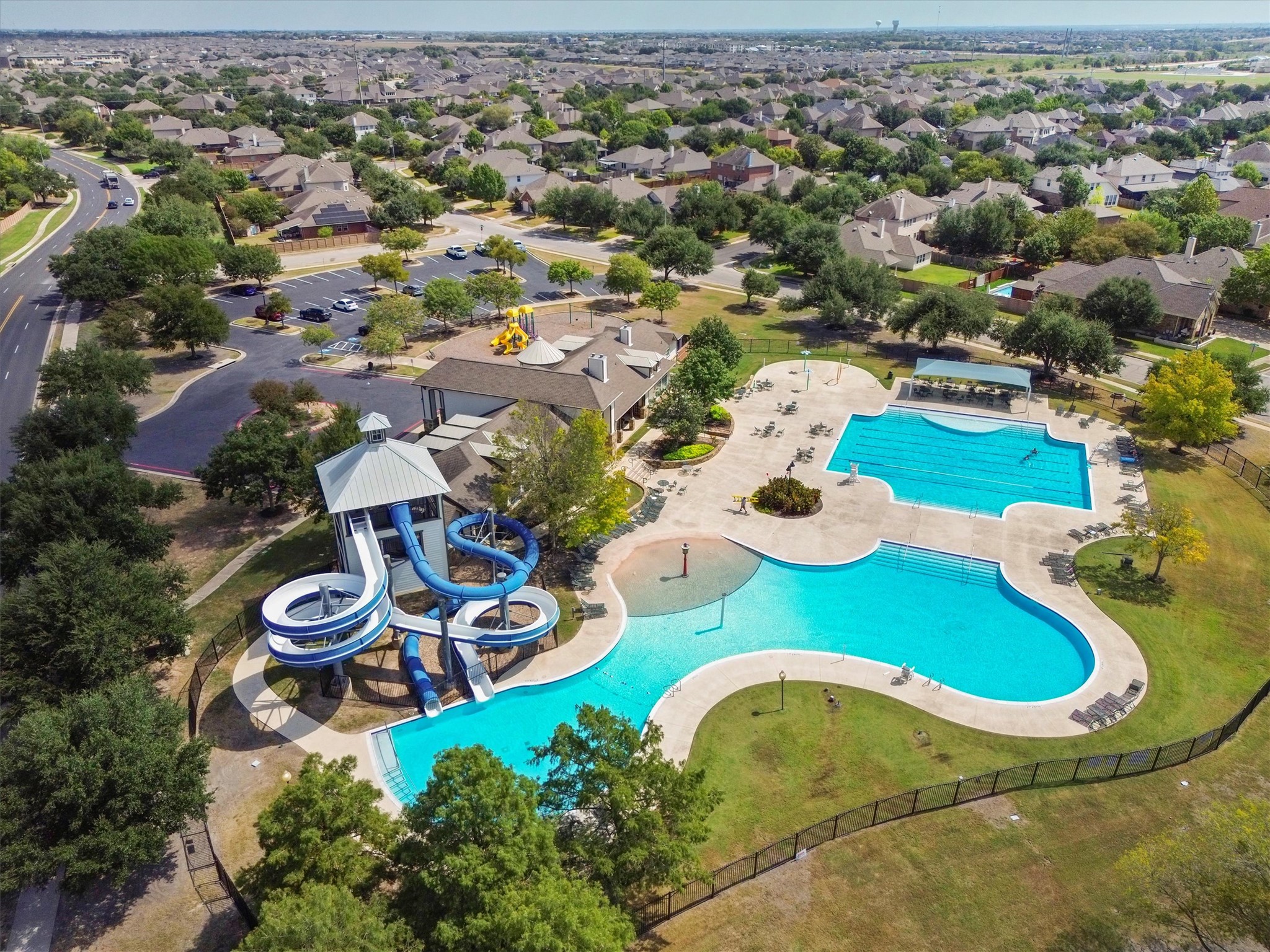 11701 Jackson Falls Way Manor, TX 78653 - Photo 32 of 40 An aerial perspective reveals a vibrant community pool with multiple slides and a clubhouse, encircled by residential homes.