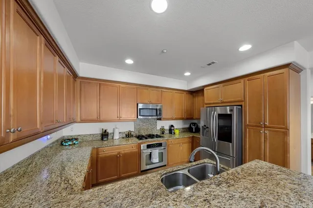 a kitchen with stainless steel appliances granite countertop a refrigerator sink and stove