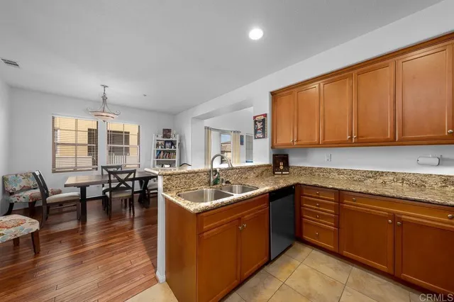 a kitchen with stainless steel appliances granite countertop a sink dishwasher stove and wooden cabinets with wooden floor