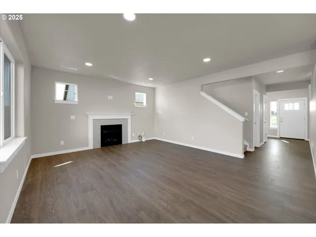 a view of an empty room with wooden floor and a fireplace
