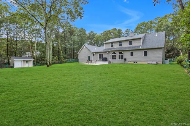 a view of a house with a big yard and large trees