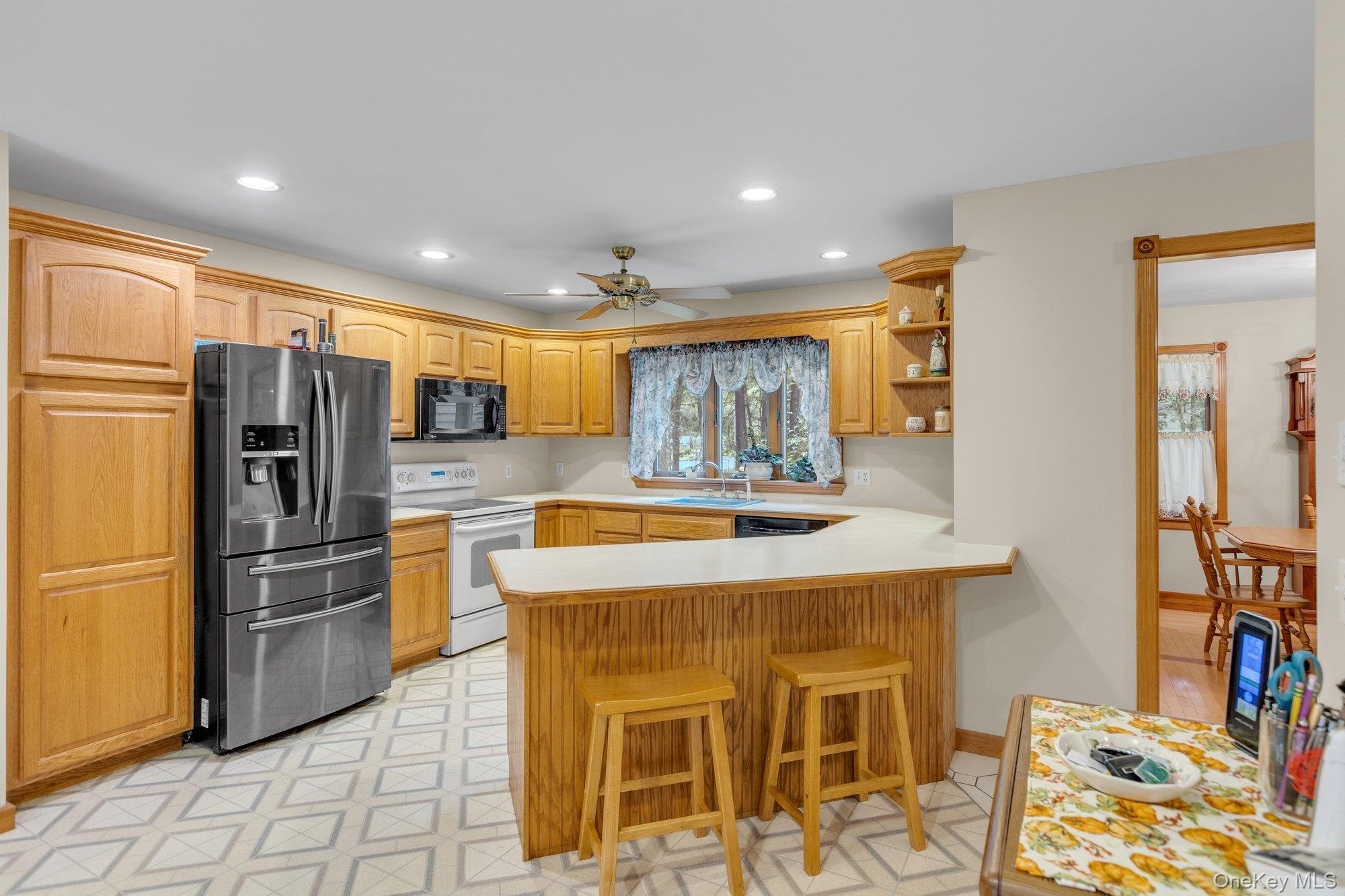 501 Wading River Road Manorville, NY 11949 - Photo 8 of 31 Kitchen featuring stainless steel fridge with ice dispenser, white electric range, light countertops, a breakfast bar, and open shelves
