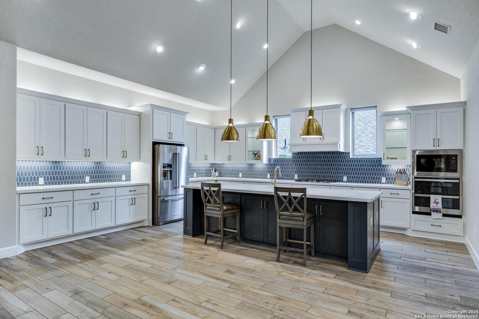 10027 Sarah Place Boerne, TX 78006 - Photo 9 of 47 a large kitchen with kitchen island a sink white cabinets and stainless steel appliances
