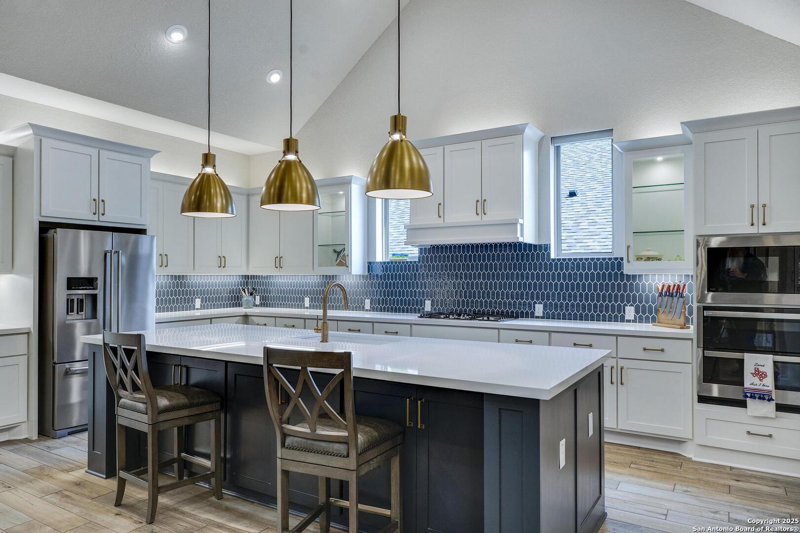 10027 Sarah Place Boerne, TX 78006 - Photo 10 of 47 a kitchen with stainless steel appliances a sink a stove a refrigerator cabinets and chairs