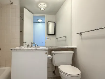 a bathroom with a granite countertop toilet sink and mirror