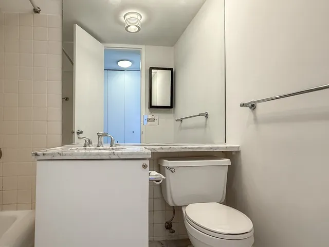 a bathroom with a granite countertop toilet sink and mirror