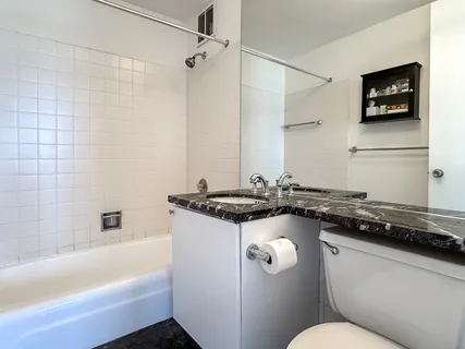 a bathroom with a granite countertop sink a toilet a mirror and bathtub