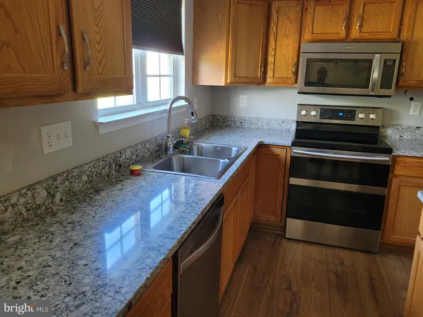 a kitchen with granite countertop a stove a sink and a microwave