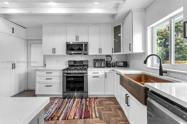 a kitchen with white cabinets appliances and a sink