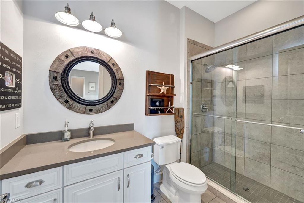 9206 Marble Stone Drive Naples, FL 34120 - Photo 33 of 50 a bathroom with a granite countertop toilet a sink a mirror and a shower