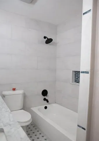 a white toilet sitting next to a bath tub