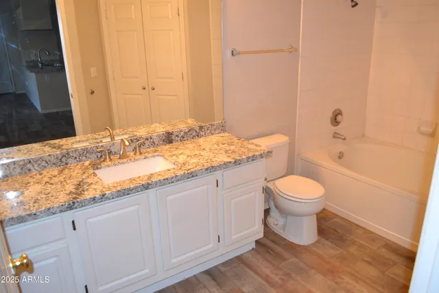 a bathroom with a granite countertop sink a toilet and bathtub