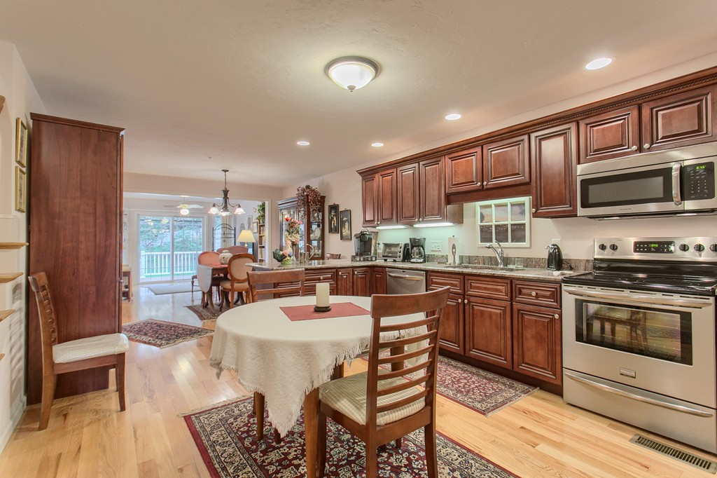 14 Riley Road, Unit 14 Lunenburg, MA 01462 - Photo 8 of 30 a large kitchen with stainless steel appliances granite countertop a stove a sink dishwasher a dining table and chairs with wooden floor
