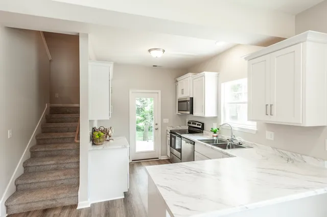 a large white kitchen with wooden floors and stainless steel appliances